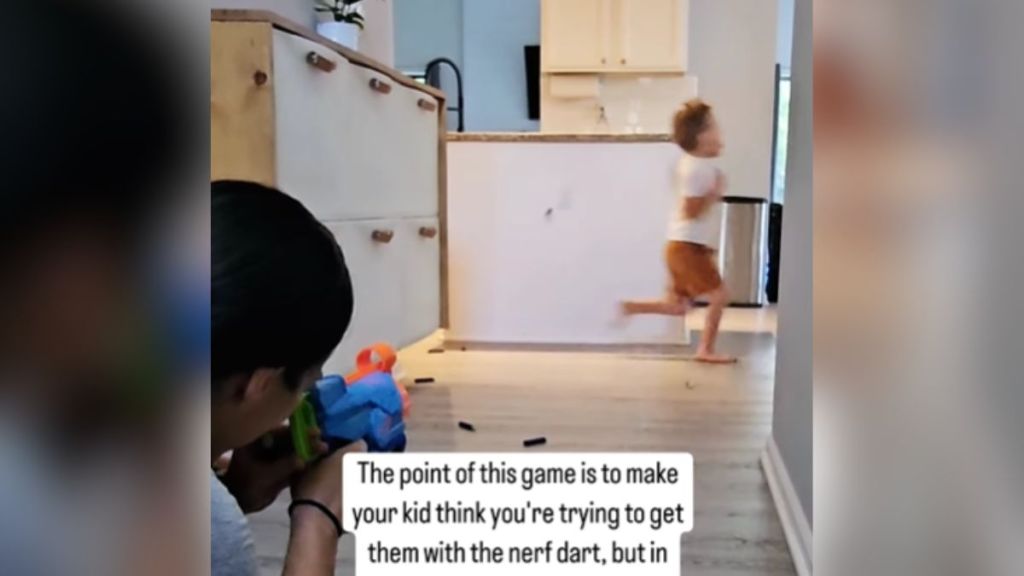 A woman shooting Nerf darts at her small son.