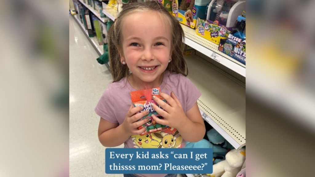 A little girl holding an item in a store and smiling.