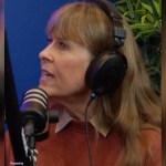 Terri Irwin looks to the side as she talks. She's wearing headphones and is talking into a podcast mic