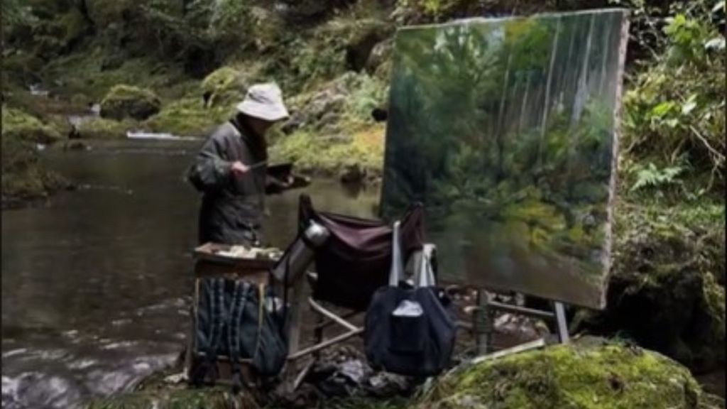 Image shows an old Japanese painter on a small outcropping of land in the middle of a river.