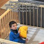 A baby in a playpen holding a toy.