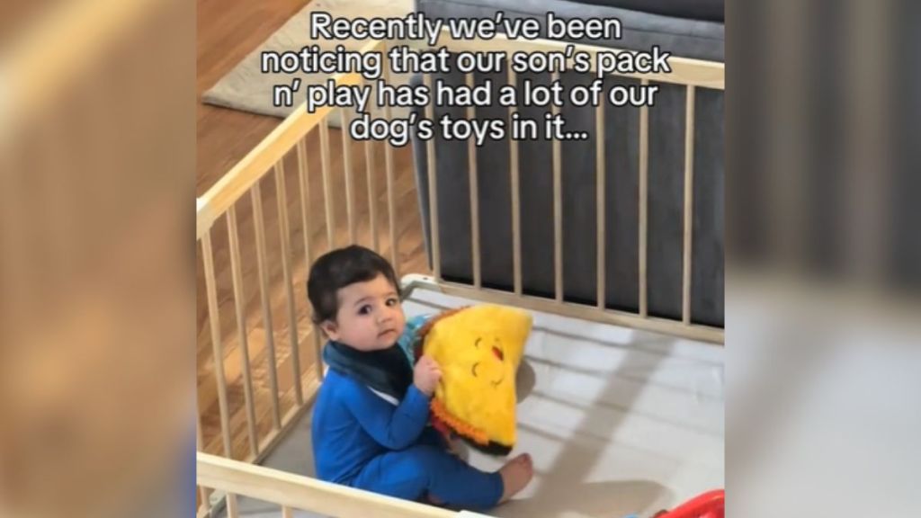 A baby in a playpen holding a toy.