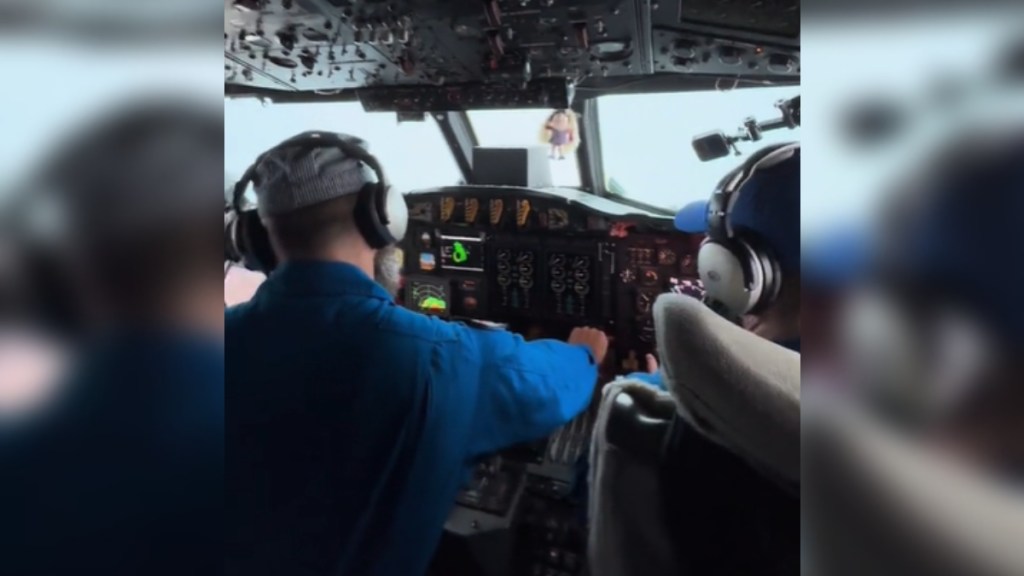 View from behind of two pilots in a cockpit. There's not much visibility with the hurricane