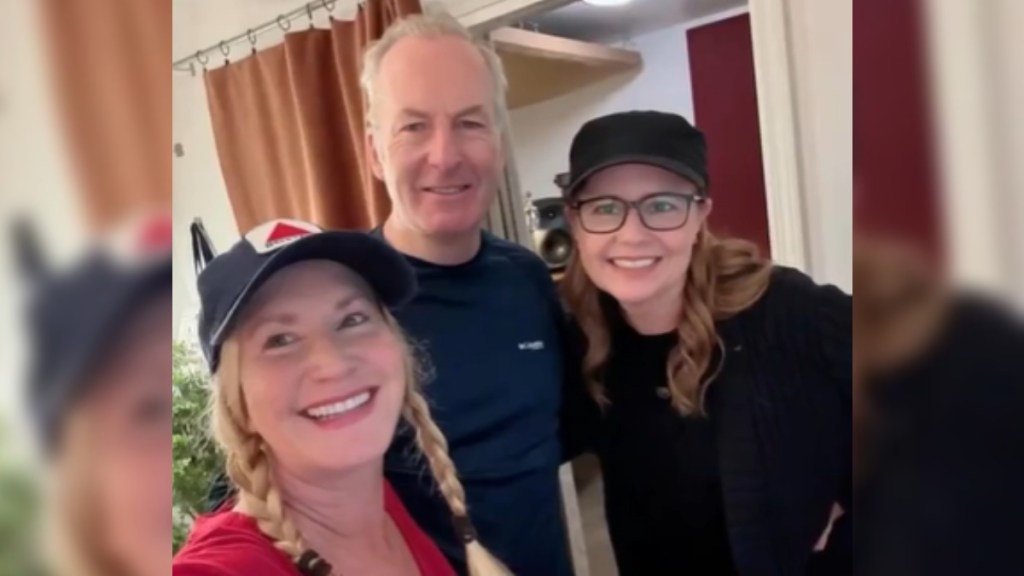 Jenna Fischer and Angela Kinsey smile as they pose with a man who is also smiling