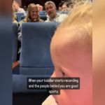 A toddler filming the people behind her.