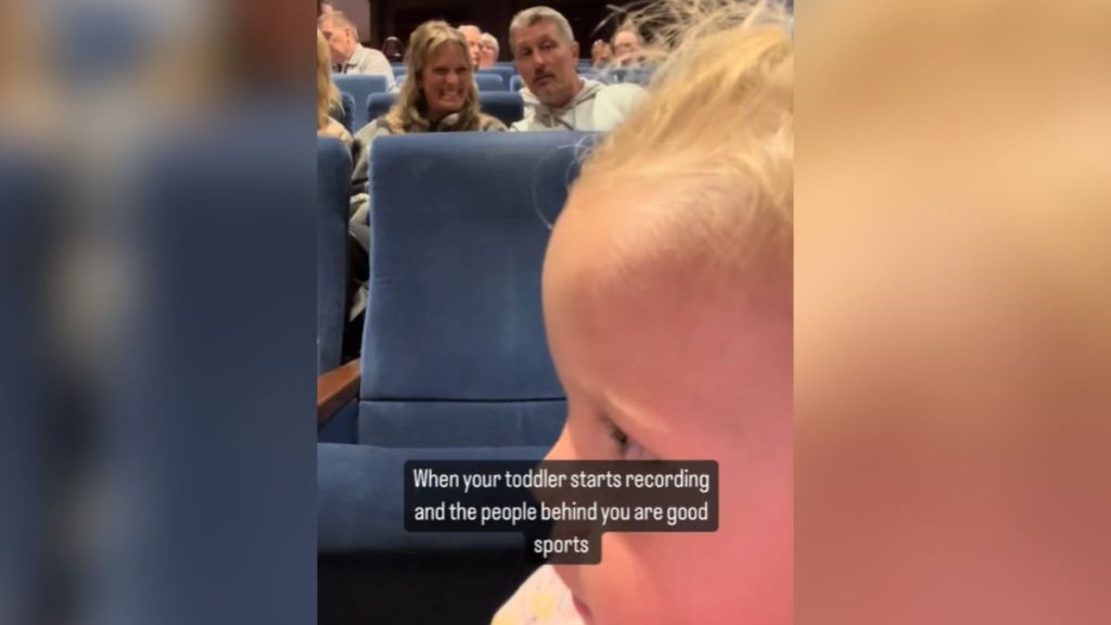 A toddler filming the people behind her.