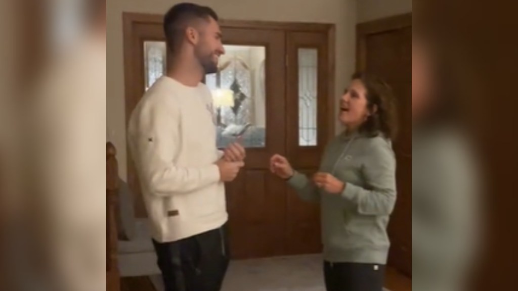 A woman and young man smile as they talk to one another. The woman looks a bit nervous