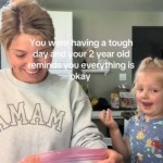 A woman smiles as she looks down at the bag in her hand. Her toddler smiles wide, looking into the camera. Text on the image reads: You were having a rough day and your 2 year old reminds you everything is okay