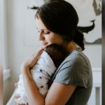 A mother holding a swaddled newborn baby.