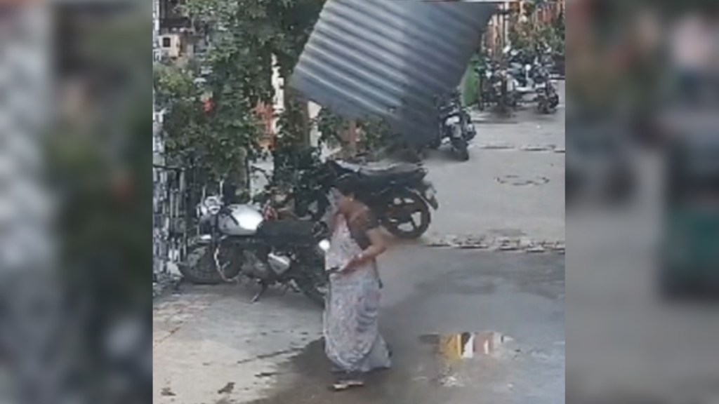 A woman walks down a street. A massive water tank is just above her head and is about to fall onto her