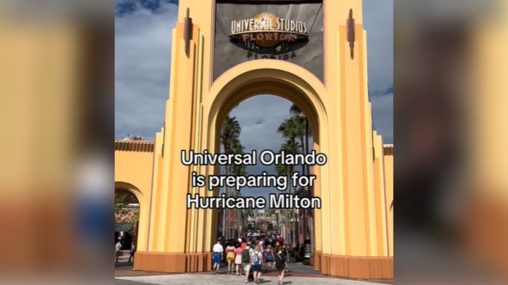 View of the entrance to Universal Studios. There are groups of people entering. Text on the image reads: Universal Orlando is preparing for Hurricane Milton