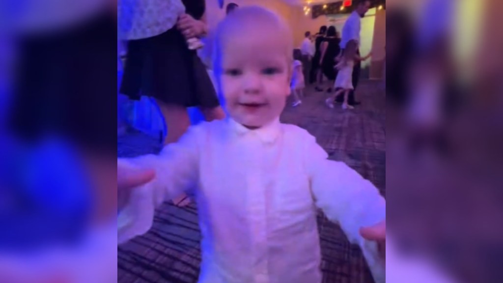 A toddler runs toward the camera, arms out to grab it.