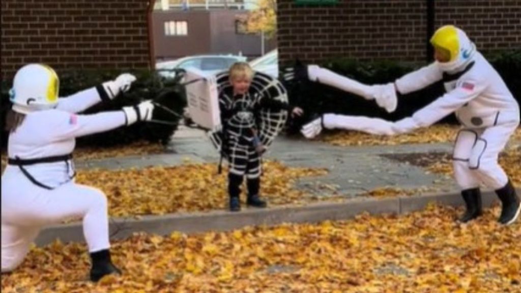 Image shows a child in a black hole costume with two astronauts being sucked in.