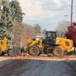 Image shows two tractors and a dump truck performing a ballet-like performance while doing bulk leaf pickup.