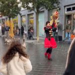 A woman in a costume leading a parade of geese.