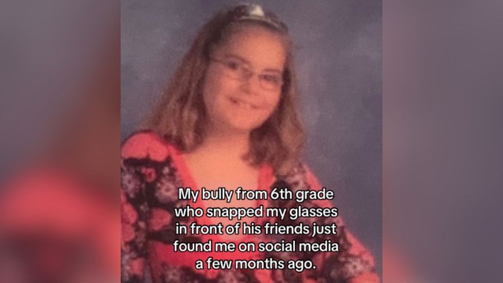 A young girl wearing glasses against a grey backdrop.