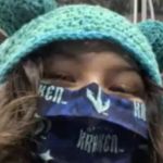 A young woman wearing a knitted hat at a hockey game.