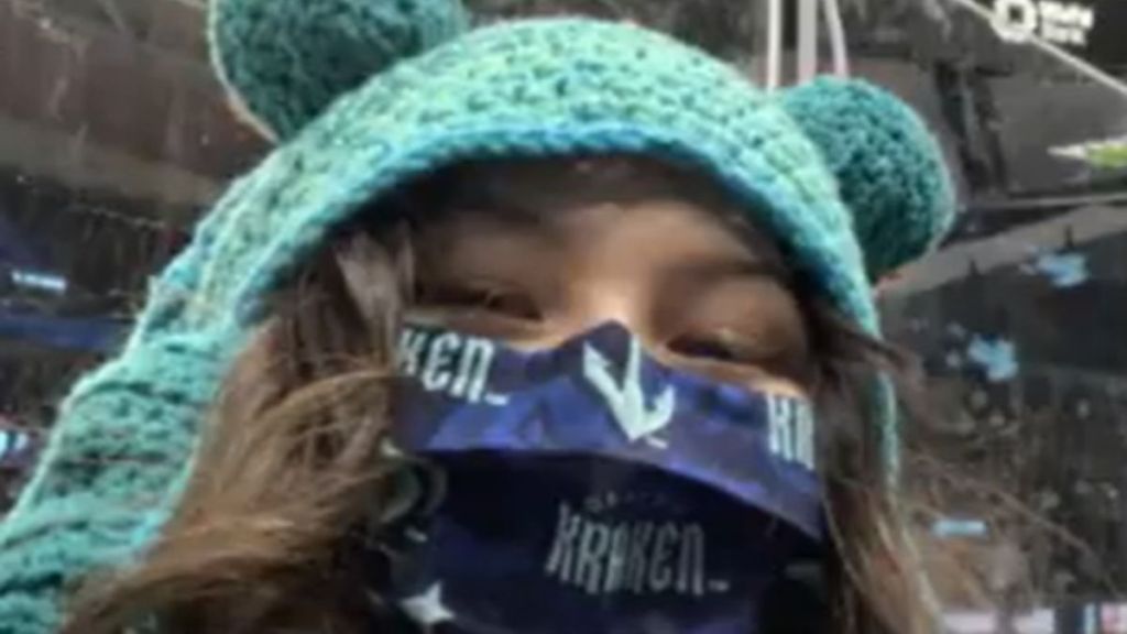 A young woman wearing a knitted hat at a hockey game.