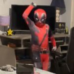 A child in a Deadpool costume dancing in his room.