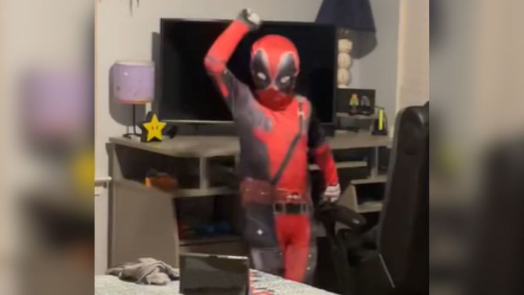 A child in a Deadpool costume dancing in his room.