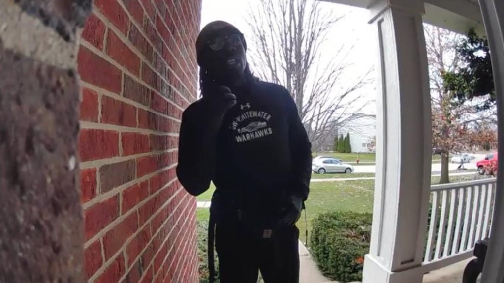 View of a mailman standing on the front porch of the man he is trying to rescue