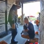 View of a front porch from the doorbell cam. A woman squats with her child in her arms. She looks down at him. A man stands next to them, door still open as he joins them.