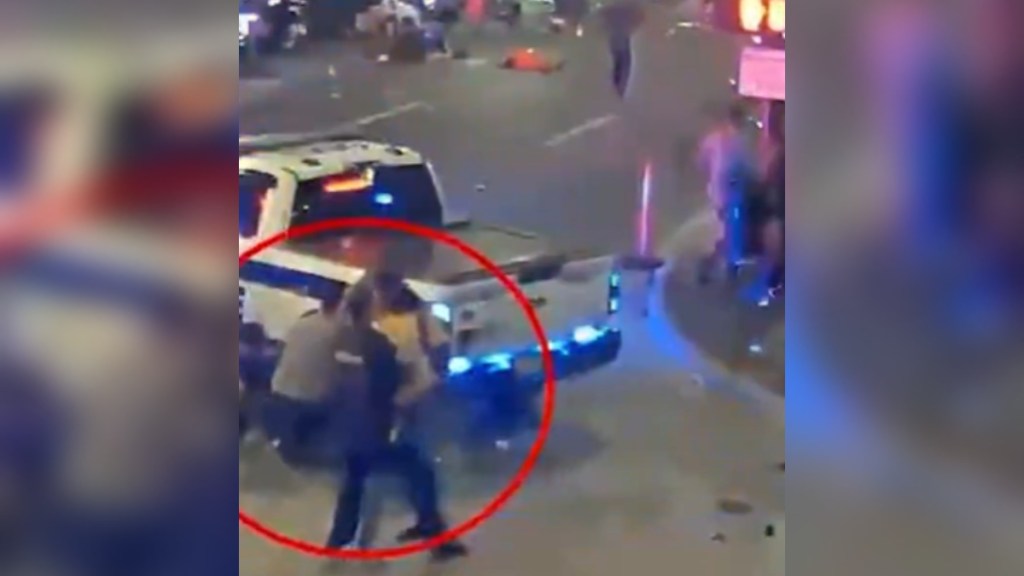 Street camera footage of downtown Orlando. People scatter in the distance as a cop tries to take down a shooter. The image is edited so there is a red circle indicating the location of the shooter and cop