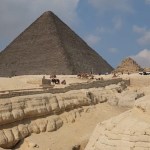 Distant view of the pyramids in Egypt, bright blue sky with white fluffy clouds behind them