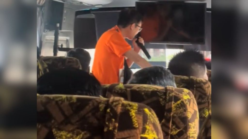 A tour guide in an orange shirt using a microphone.