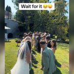 Guests lined up and facing each other at a wedding with the bride and groom at the head.