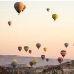 Image shows several hot air balloons flying during a balloon festival.