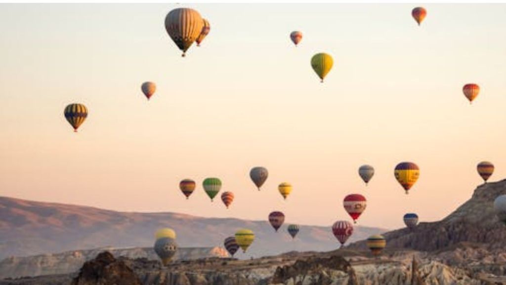 Image shows several hot air balloons flying during a balloon festival.