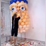 A man creating an art display out of balloons.