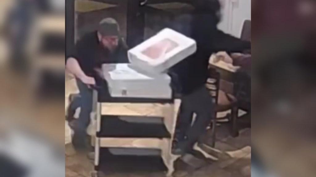 Security cam footage of a barista shoving a cart into a robber