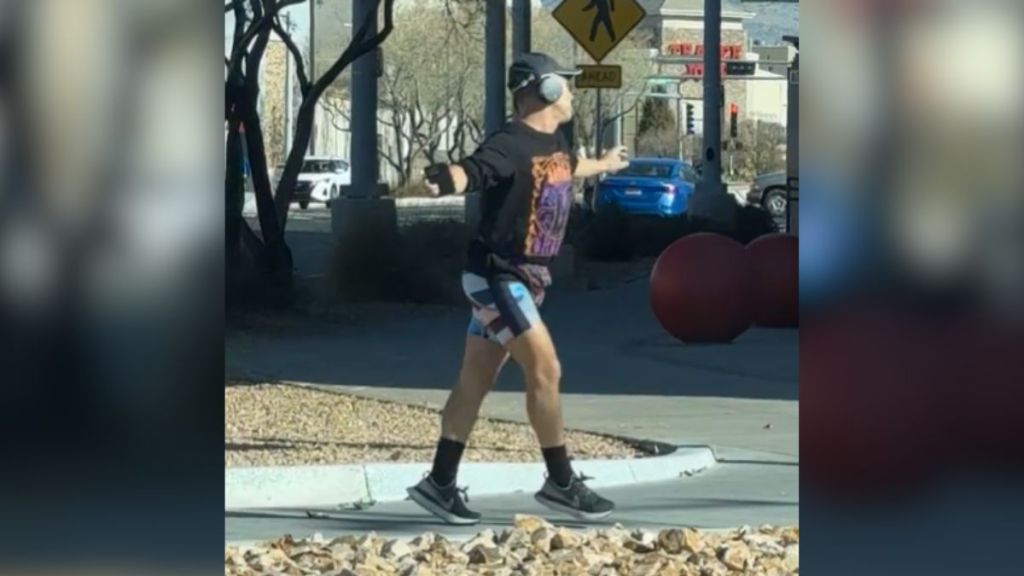 A man dancing outside in a public place while wearing headphones.