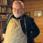 Close up of an older man smiling as he ties on his apron.