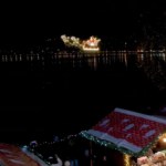 Distant view of Santa flying pas in a sleigh in the sky above festive buildings