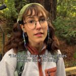 A woman with glasses standing in the woods.