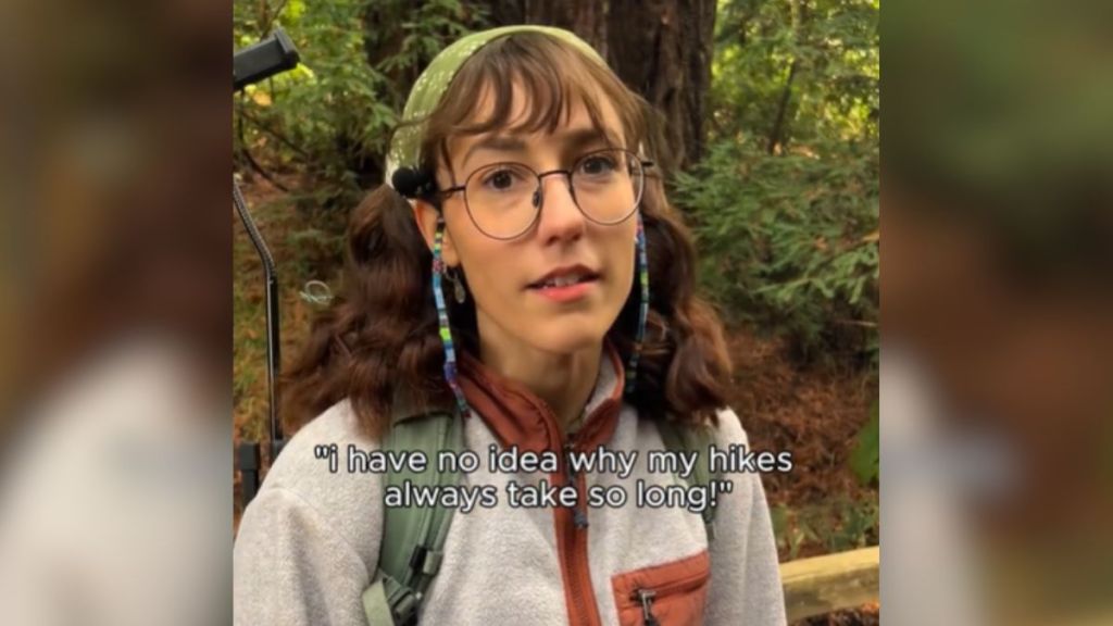 A woman with glasses standing in the woods.