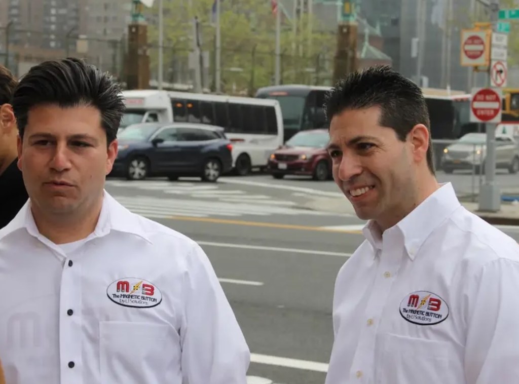 Michael and David Puglia stand outside near a busy road, talking to someone who can't be seen in this image.