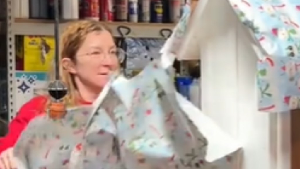 Close up of a woman as she unwraps a mysterious object that is wrapped in Christmas wrapping paper. The woman is super focused on opening the gift