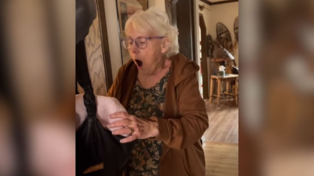 An elderly woman looking inside a bag with a surprised expression on her face.