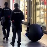 View from behind of two police officers in China as the walk alongside a spherical robot