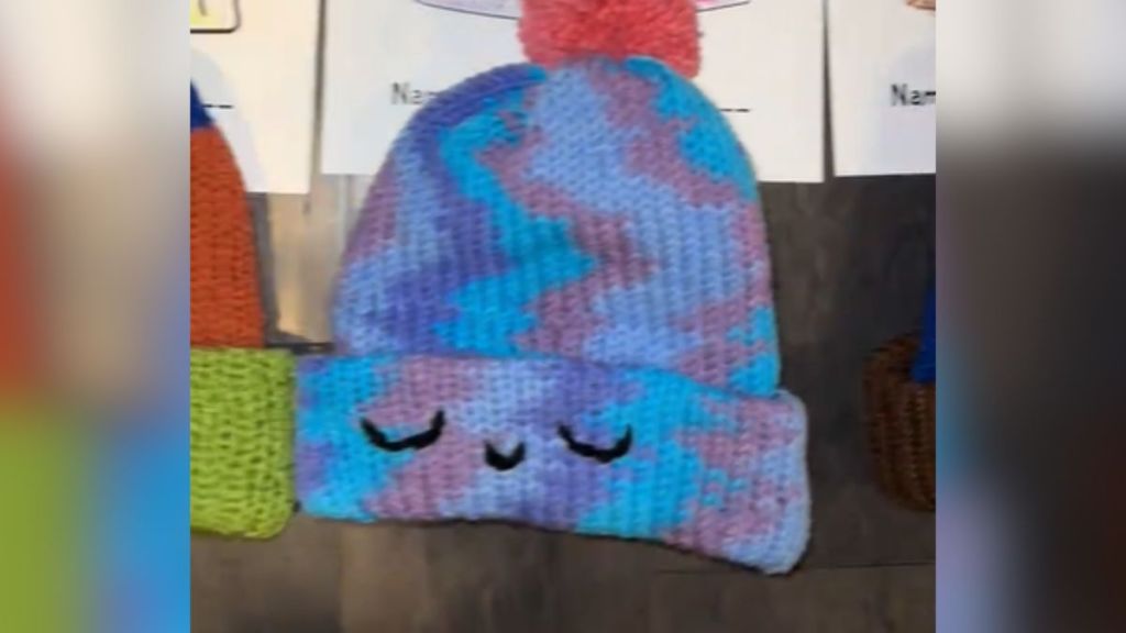 A colorful winter hat with a smiling face on it.