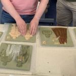 Image shows Livings Paintings book making process while a "test" reader examines a proof page.