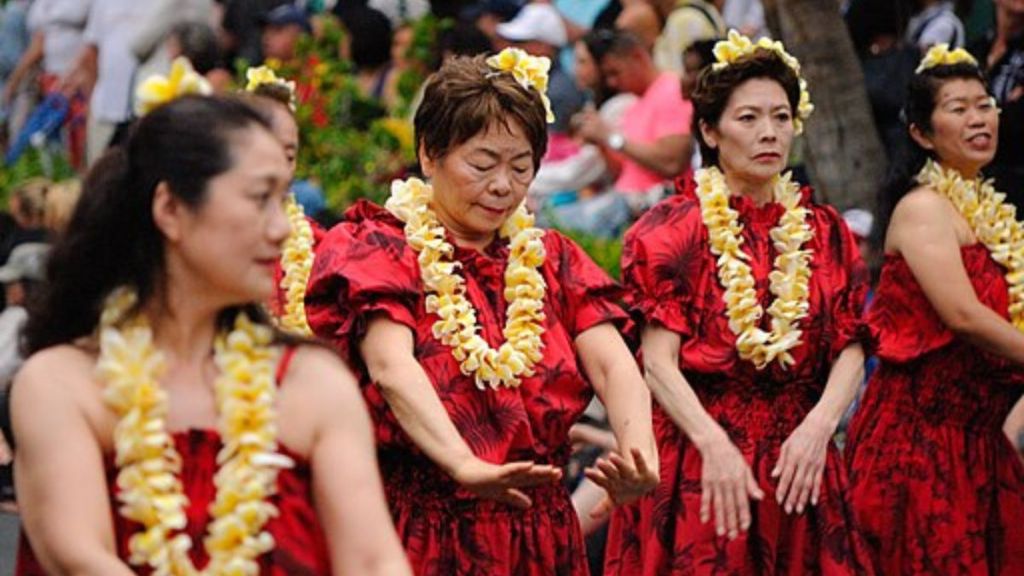 Image show Hawaiin dancers wearing yellow leis.