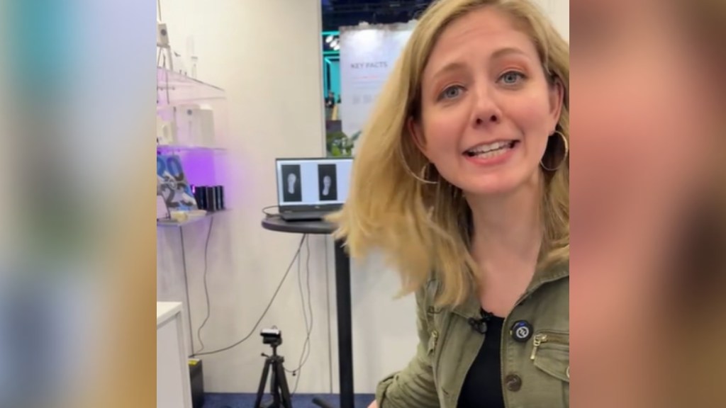 A woman excitedly talks as she stands near a machine that scans shoes for TSA.