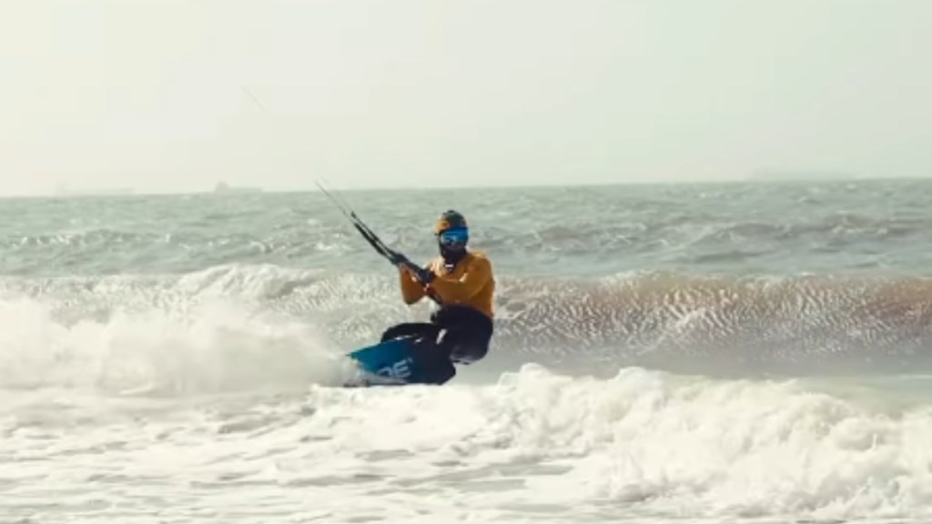 Olympic athlete Bruno Lobo rides a kike on an ocean wave