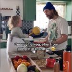 A dad talking to his toddler, who is sitting on the counter.