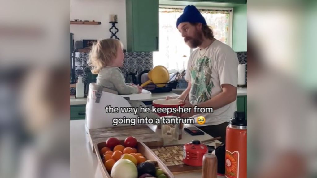 A dad talking to his toddler, who is sitting on the counter.